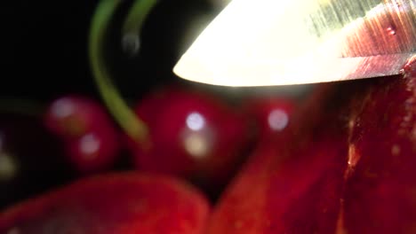 sharp and shining knife trying to slice cherry in half