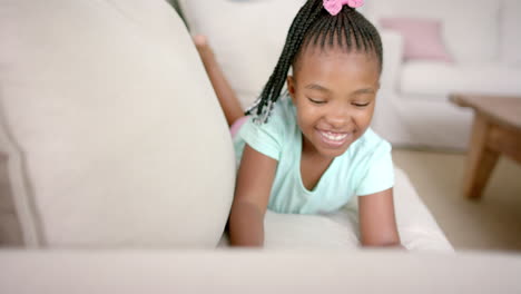 an african american girl with braided hair and a pink bow smiles brightly at home with copy space