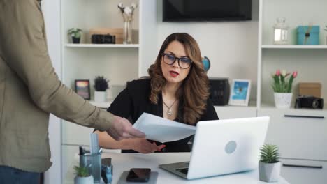 El-Empleado-Ingresa-A-La-Oficina-De-Su-Directora,-Muestra-Varios-Documentos,-A-Lo-Que-La-Mujer-Reacciona-Con-Descontento,-Hace-Un-Comentario-Al-Empleado-Y-Lo-Expulsa