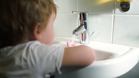 boy washing hands with soft soap and turning off water