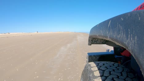 Neumático-Delantero-Izquierdo-Del-Vehículo-Y-Dunas-De-Arena-Mientras-Conduce-En-Una-Playa-En-Un-Día-Soleado-En-La-Isla-Del-Padre-Sur,-Texas--Punto-De-Vista,-Punto-De-Vista