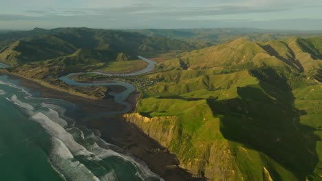 marokopa beach panning to kiritehere beach during sunset, golden glow on landscape, new zealand coastal landscape, aerial