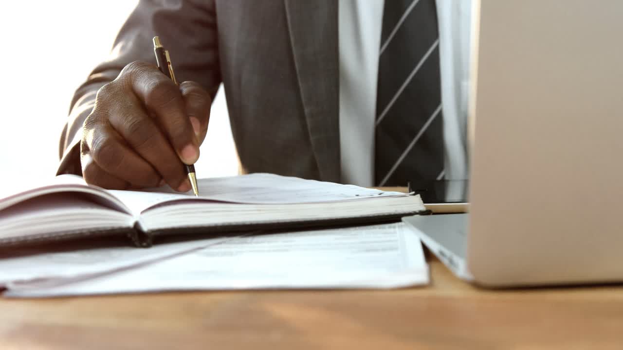 Uomo d'affari che scrive su un diario mentre usa il portatile