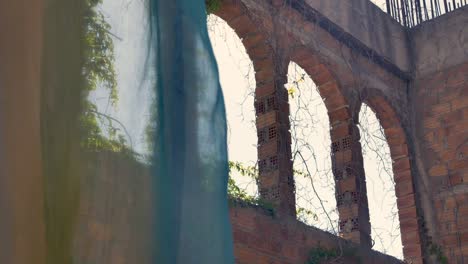 a shot looking through coloured curtains at interesting stone archways outside