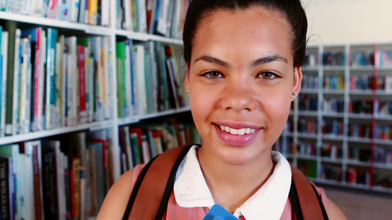 Portrait of happy schoolgirl standing in library