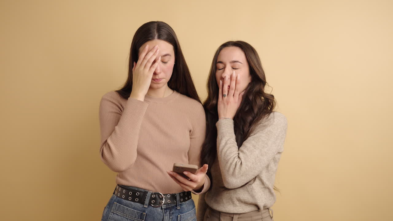 Two young women receiving bad news on smartphone