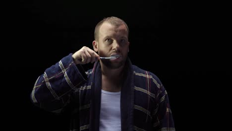 man brushing teeth in bathrobe