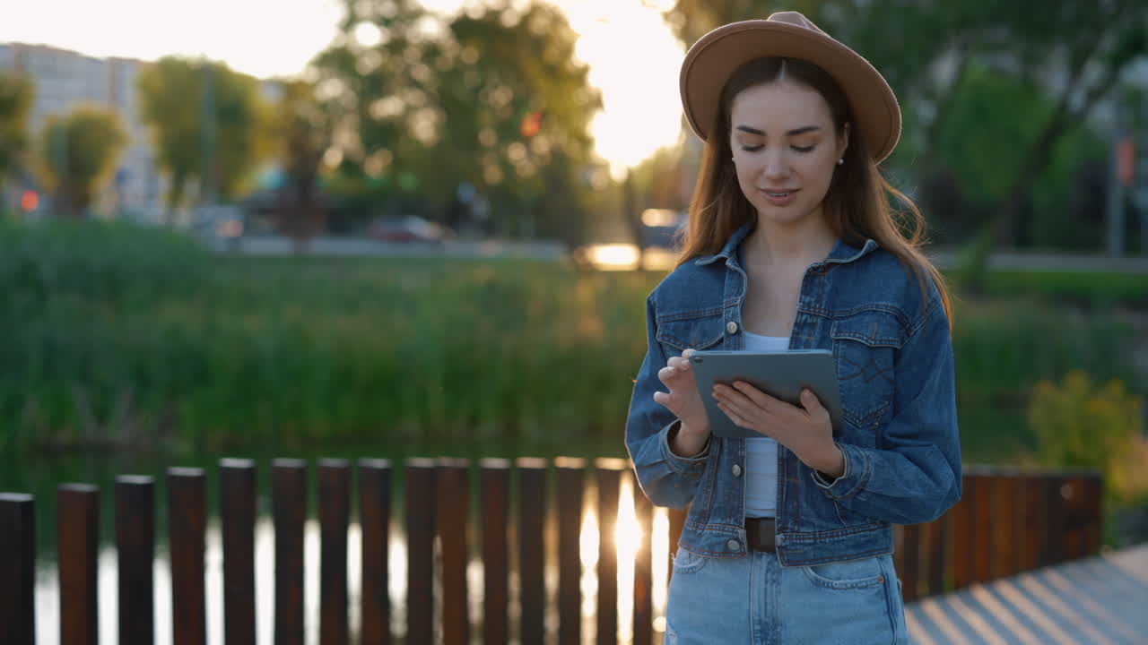 Woman using tablet in park at sunset