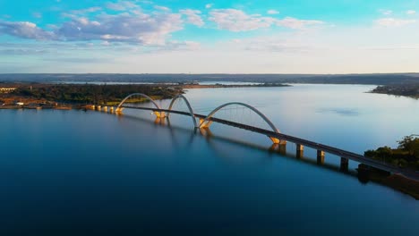 static aerial hd drone footage of the paranoa lake and jk bridge in brasilia, brazil with cars moving across the bridge in the distance