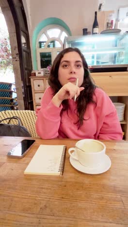 young woman brainstorming and taking notes in cafe
