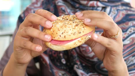 una mujer comiendo un sándwich de bagel.