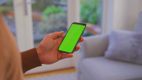 Cerca-Del-Hombre-En-Casa-Sosteniendo-El-Teléfono-Con-Pantalla-Verde-En-Blanco