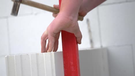 worker's hands hitting sand-lime block with straight peen hammer