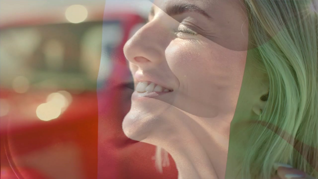 Sole che filtra dal finestrino dell'auto, facendo sì che una donna si sistemi i capelli, si rilassi, sorrida, con uno strato rosso che le accarezza il viso, e annunci.