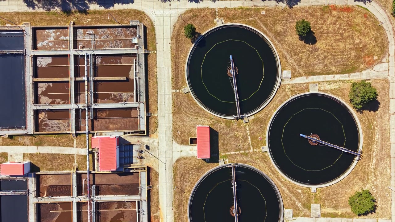 Water treatment facility in a city area with round tanks and rectangular structures during daylight hours