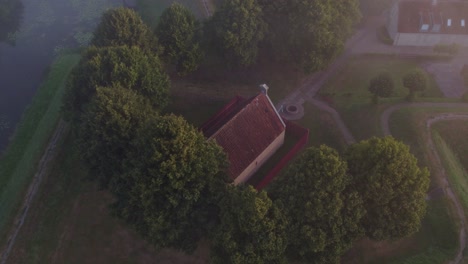 Small-chapel-at-Fortress-Bourtange-surround-by-magical-morning-fog,-aerial