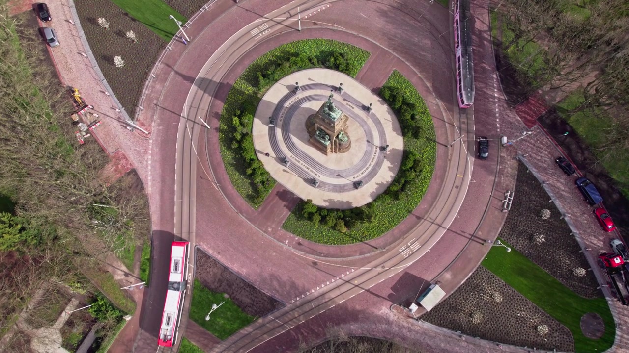 Vista aérea zenital na capital holandesa Haia, Países Baixos, com um parque de vegetação exuberante ao redor de um monumento histórico formando o centro de um cruzamento.