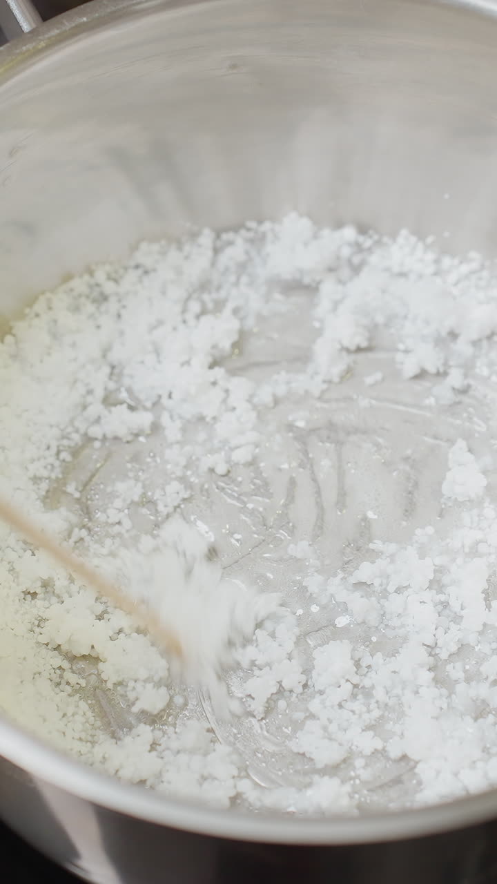 비에서 설탕을 는 여자의 손으로 보는 모습, 스토프에서 요리하는 과정, 재료 취급에 초점을 맞추고, 잘 조명된 부 환경에서 베이킹 또는 달한 요리를 만드는 준비