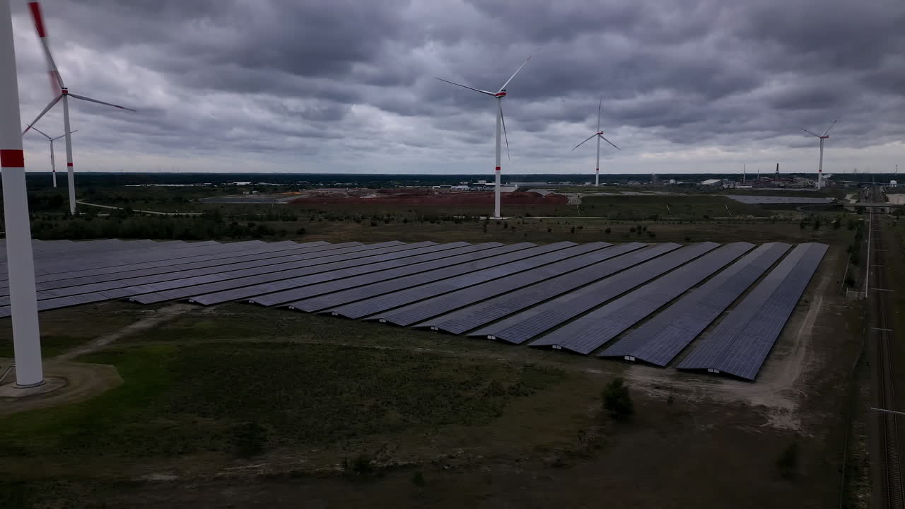 Storm clouds flowing above green energy farm, aerial drone view