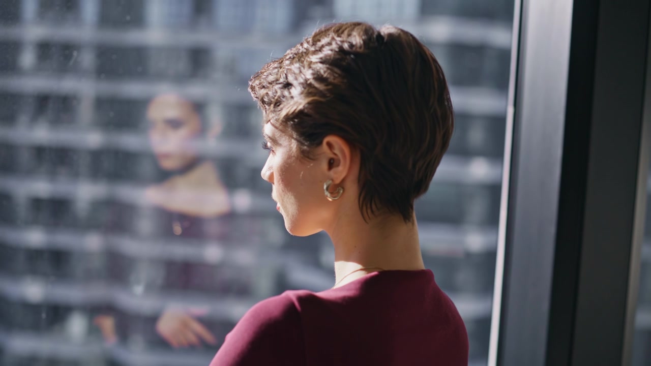 Businesswoman looking out office window with reflection, pensive lady in tower