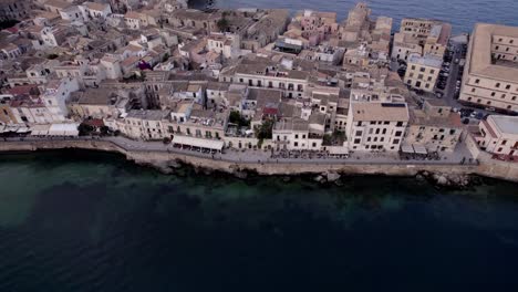 Aerial-Restaurant-filled-promenade-on-Ortigia-Island,-Sicily,-Italy