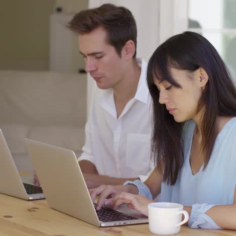 una pareja joven y tranquila sentada en la mesa usando una laptop