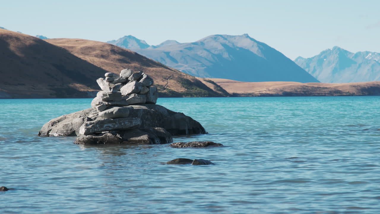 montón de rocas hechas por turistas en las impresionantes aguas turquesas del lago tekapo, nueva zelanda