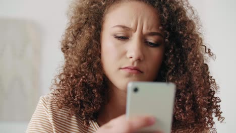 Worried teenage girl using a smart phone at home