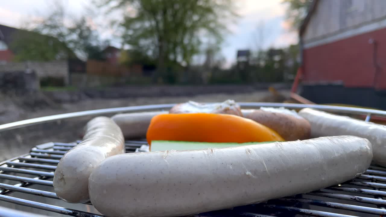 tiro macro de bratwurst alemán y verduras saludables cocinando a la parrilla al aire libre en la naturaleza