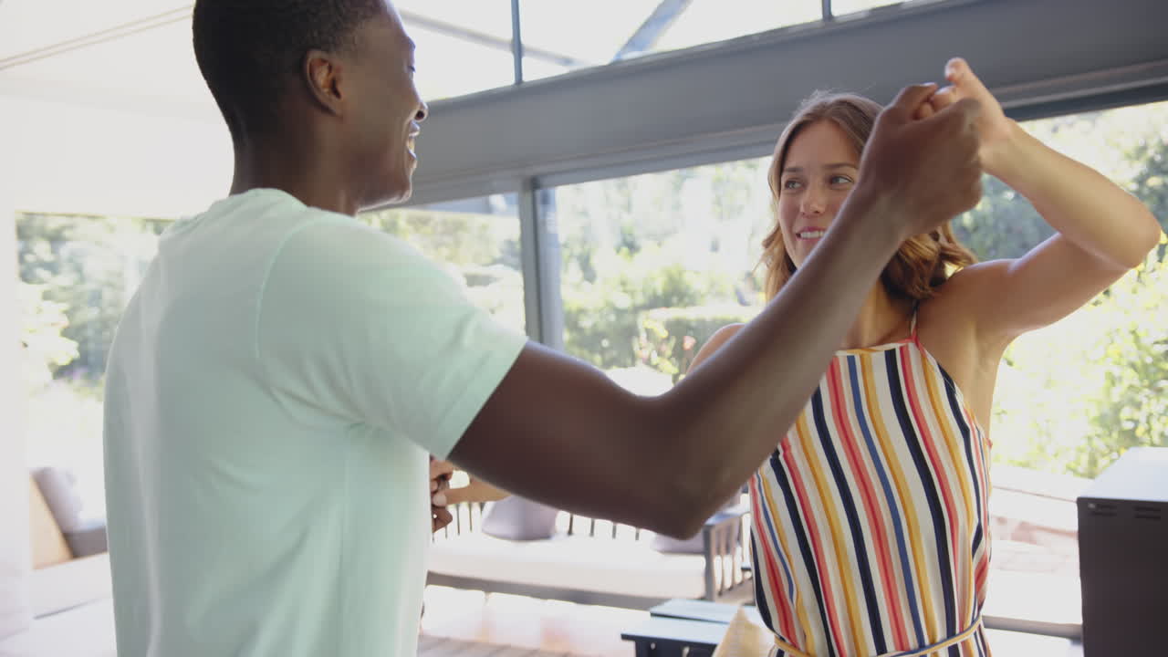 Diverse couple dancing, smiling at each other, at home