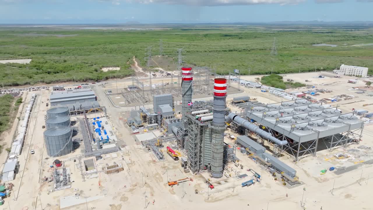 New Energy 2000 natural gas power plant under construction, industrial complex, storage silos, smokestacks, and substation in Manzanillo, Dominican Republic. Aerial drone panoramic view