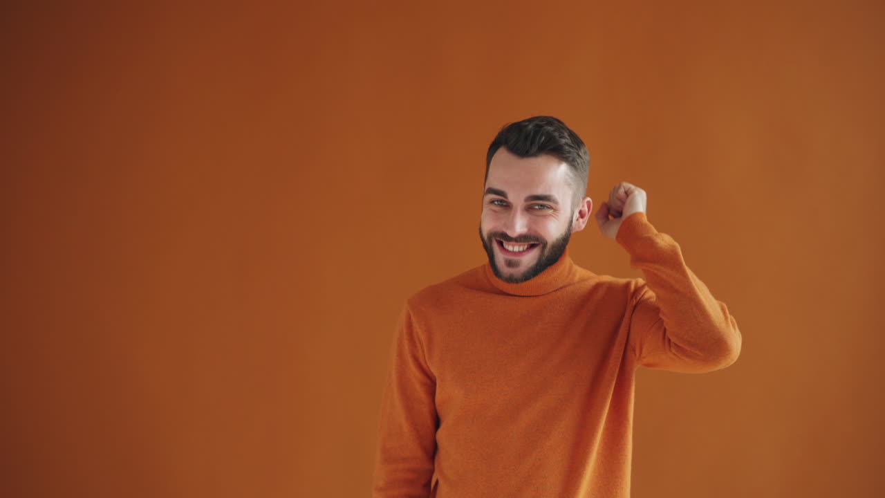 Man in Orange Sweater Expressing Happiness and Confidence