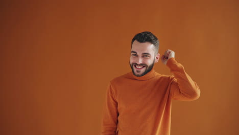 man in orange sweater expressing happiness and confidence