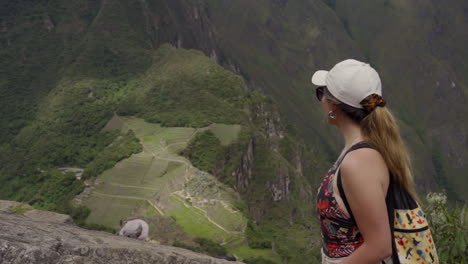 tourist woman on top of huayna picchu mountain observes machu picchu lost city