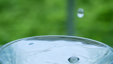 droplets of water splattering as it drops into a glass filled with clean and clear water