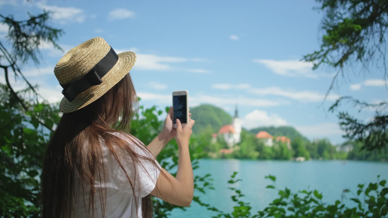 mujer tomando una foto de un hermoso paisaje de lago