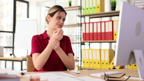woman experiencing wrist pain while working at office desk
