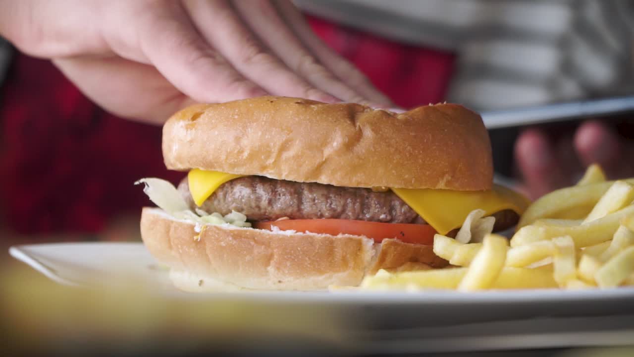 Hand squashing cheese hamburger from fast food outlet, closeup