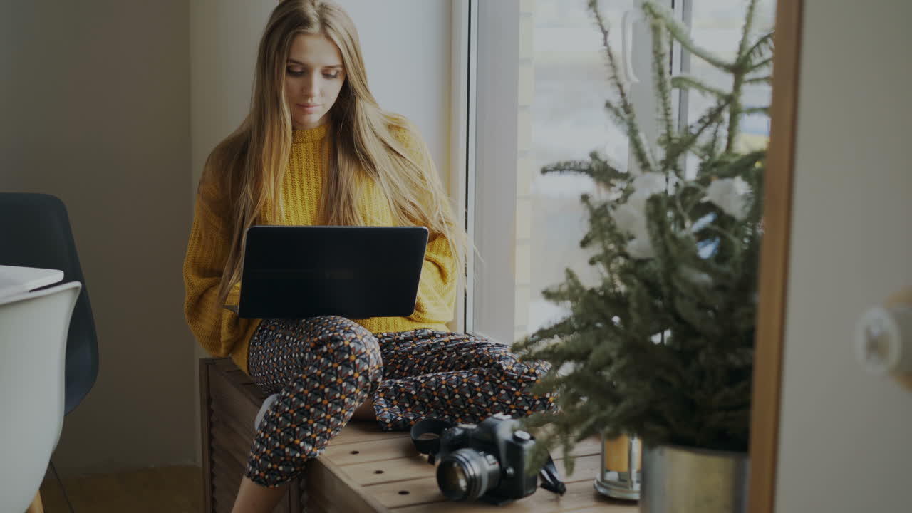 женщина, работающая из дома у окна.