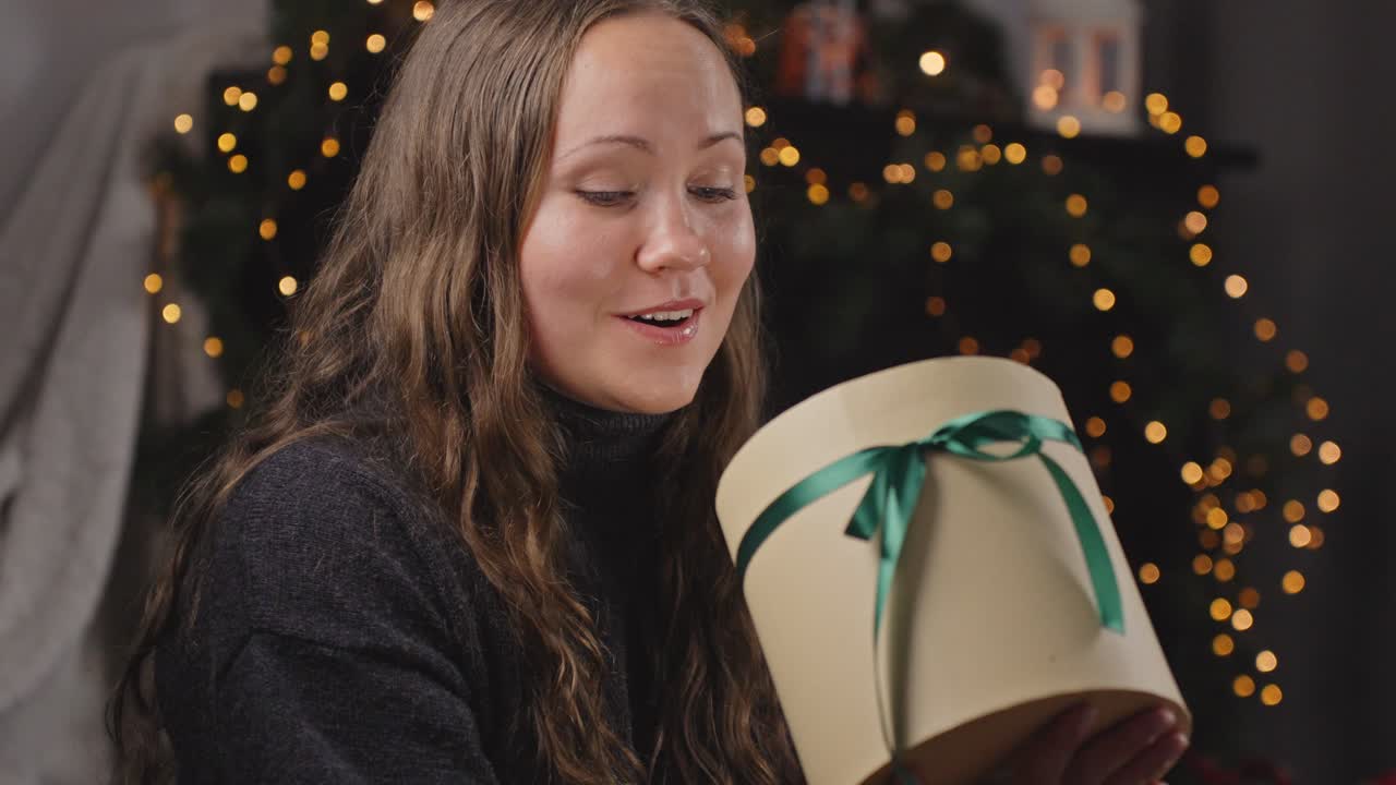 슬로우 모션으로 크리스마스 선물을 열고 있는 긍정적으로 놀라운 여성