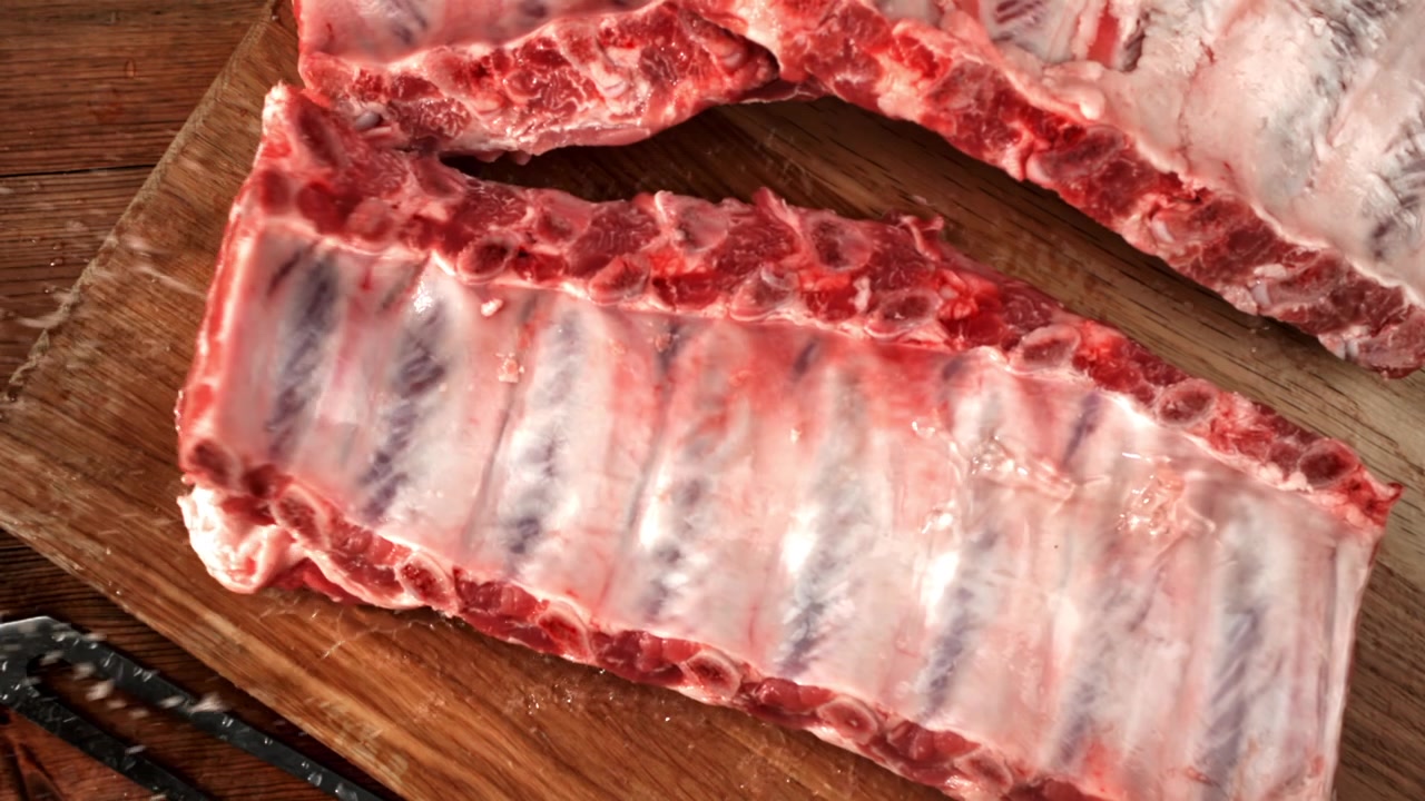 Salting Raw Pork Ribs on a Wooden Cutting Board