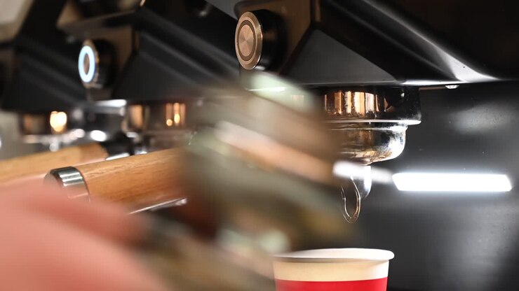 Primo piano di un barista che prepara un caffè in una caffetteria con una macchina professionale