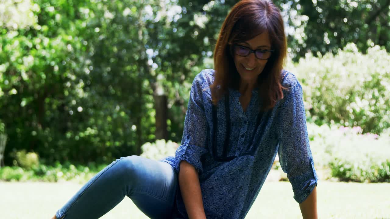Mature woman reading a book in the garden 4k