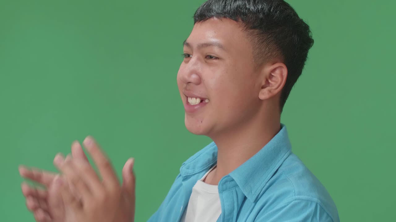 Side View Of Young Asian Man Clapping Her Hands In The Green Screen Studio