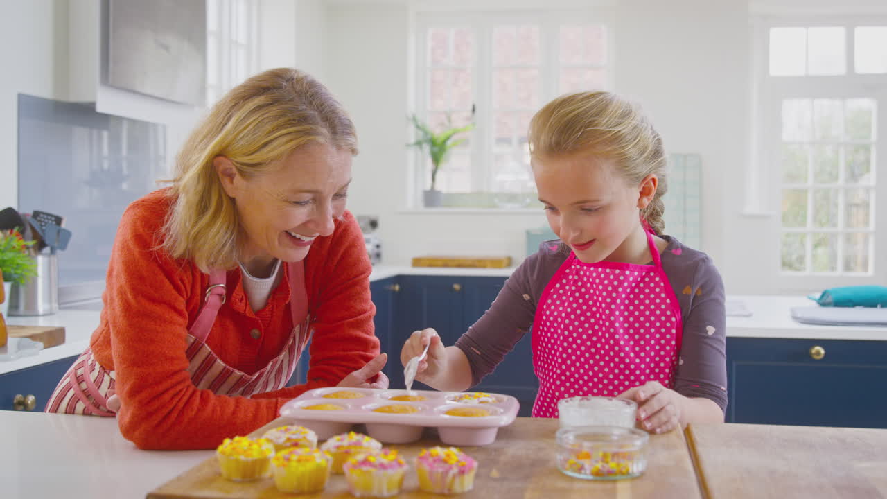 abuela con su nieta decorando pasteles caseros en el mostrador de la cocina en casa
