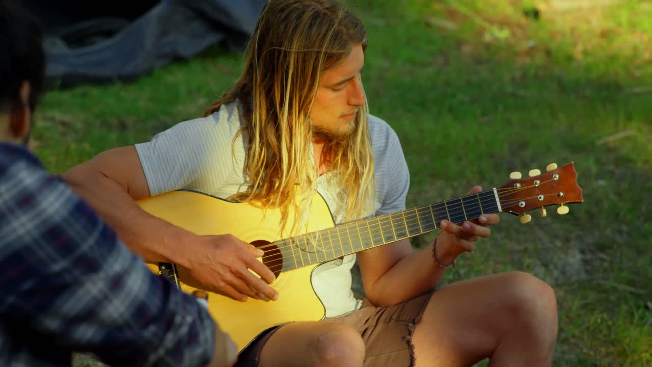 hombre tocando la guitarra en el campamento en el bosque 4k