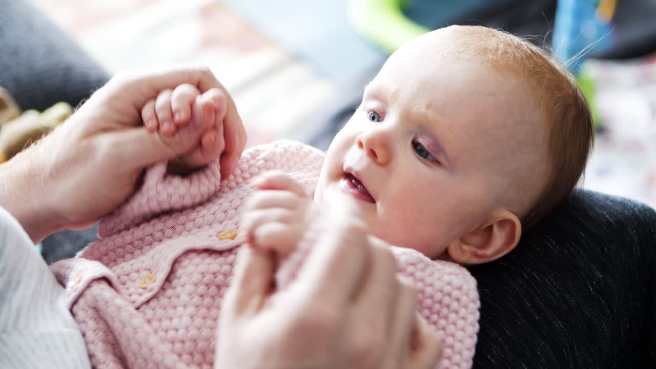아빠가 아기 딸의 팔을 움직이고 놀고 있습니다.
