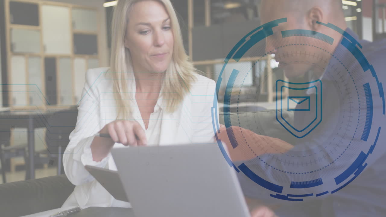 female colleague pointing laptop while male colleague leaning over reviewing tech email interface