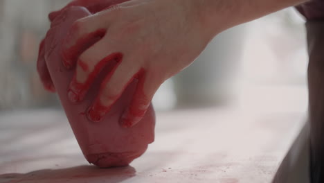 hands shaping red clay