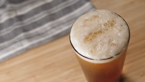 Bier-Wird-In-Ein-Pintglas-Gegossen-Und-Darin-Steigen-Blasen-Auf-Einem-Schneidebrett-Auf
